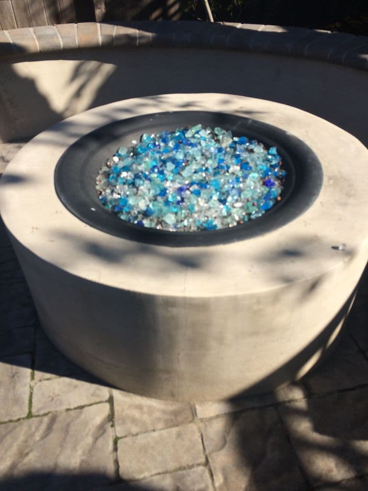 Modern concrete gas fire pit with blue fire glass on a paver patio at an Atherton estate